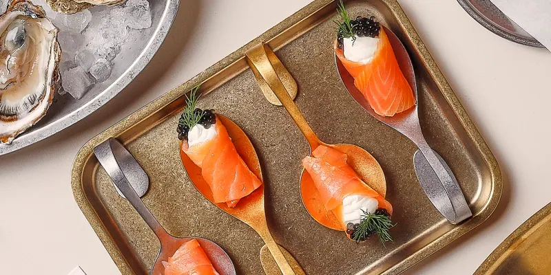 Lachsröllchen mit Kaviar auf Snacklöffeln in einem goldfarbenen Tablett der Bonbistro-Serie Serve