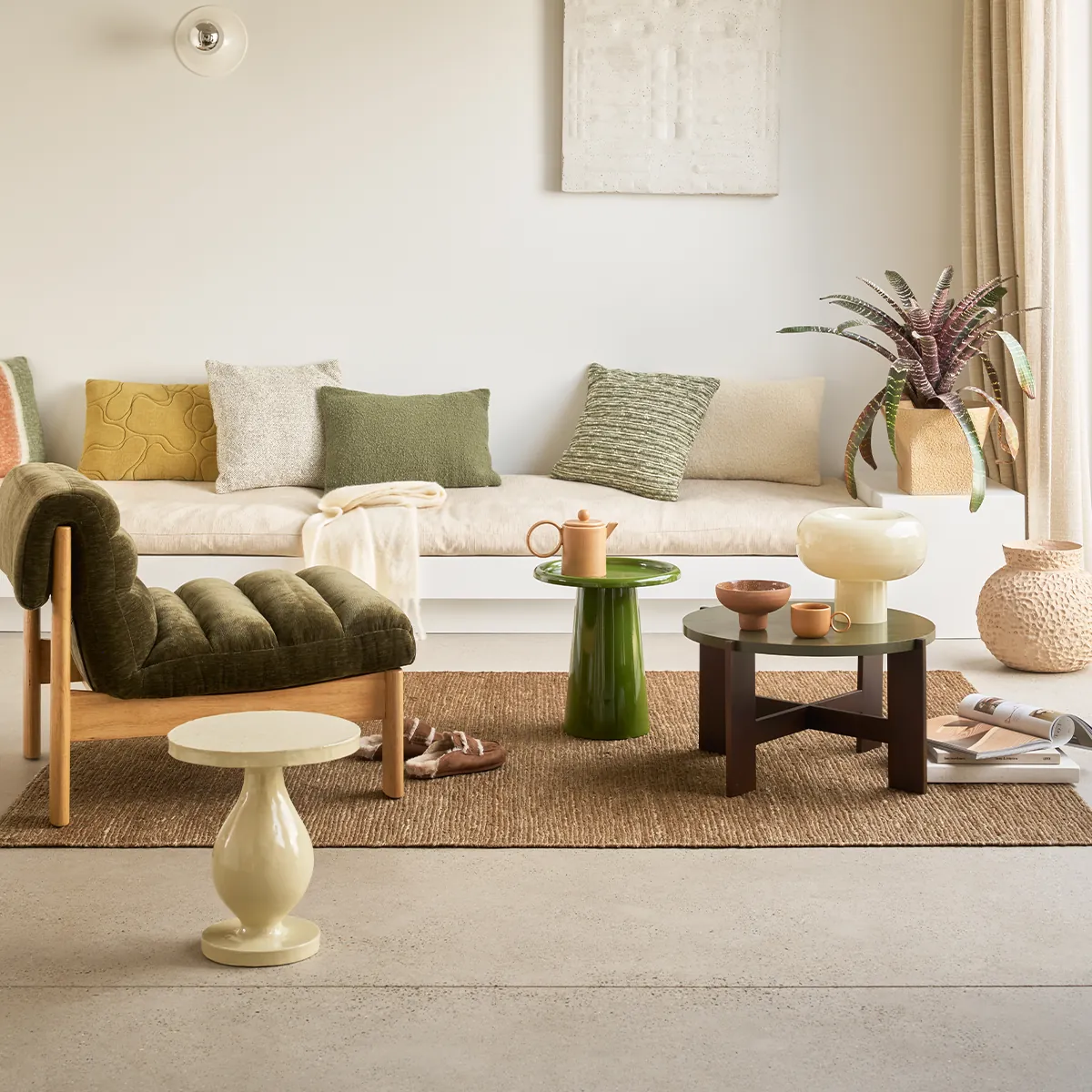 Wohnzimmer mit grünem Sessel, Beistelltischen und Keramik von Urban Nature Culture