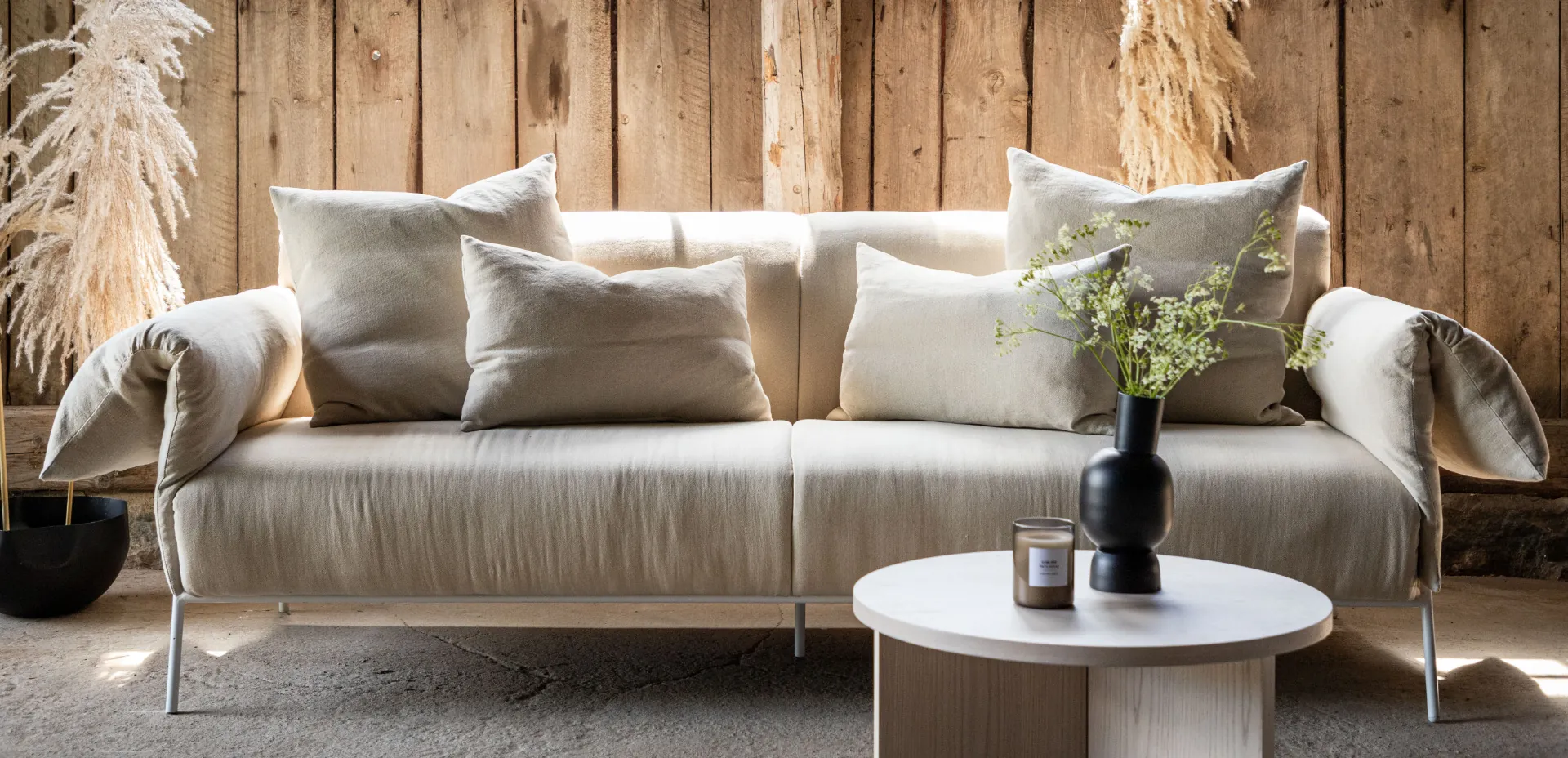 Helles Sofa von VIND Collection vor einer Wand aus Altholz